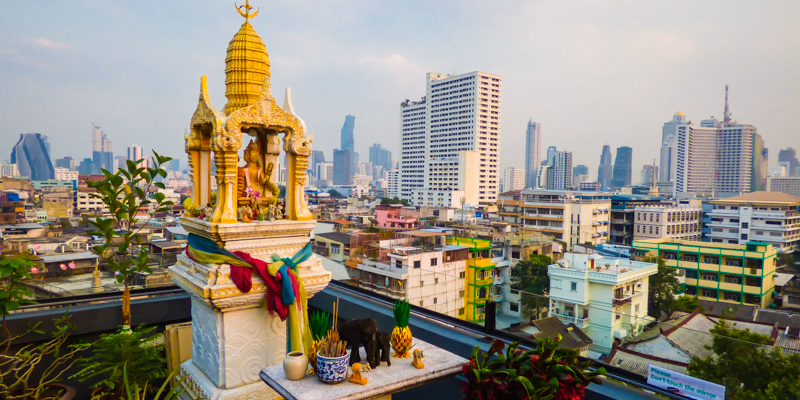 Spirit house on a rooftop and Bangkok’s skyline in the background.