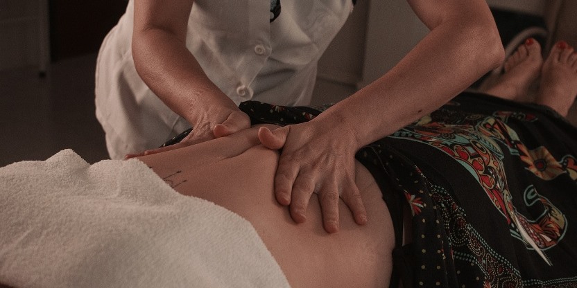 Therapist giving abdominal massage therapy