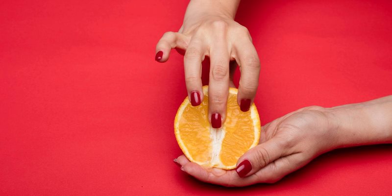 Woman fingering an orange