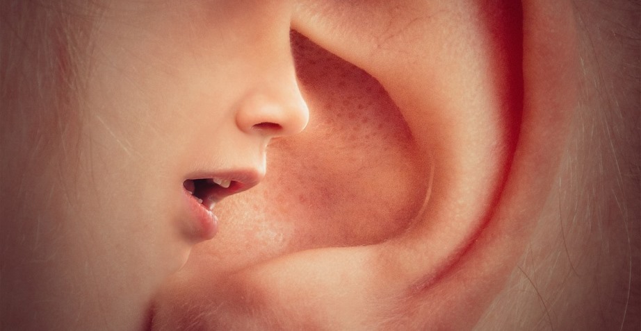 Woman whispering in ear of someone