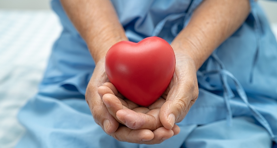 Older woman holding red heart in hands