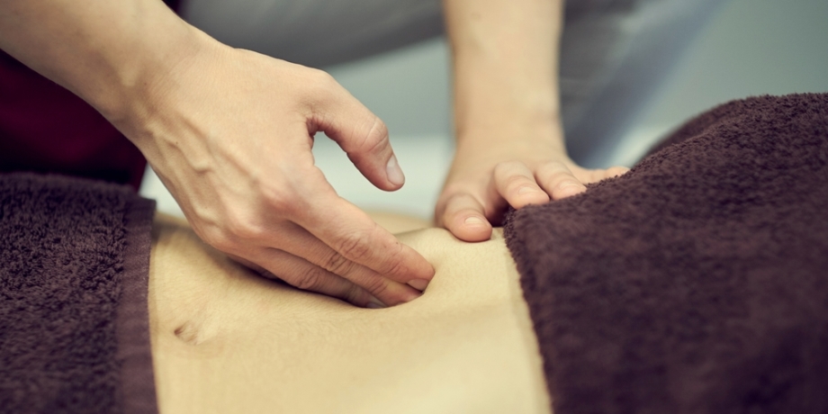 Therapist working on the client's abdomen with massage techniques