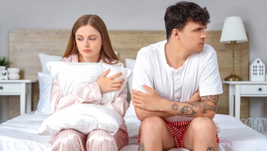 Couple seated on bed having sex problems