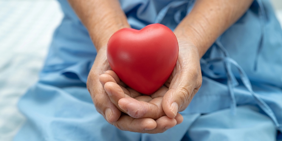 Older woman holding red heart in hands