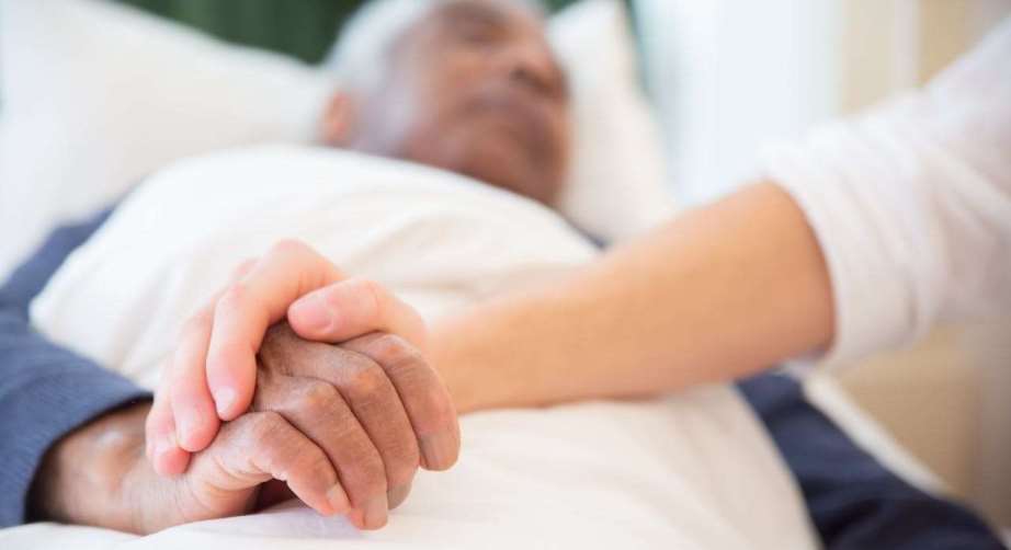 Young person holding hand of ill senior person